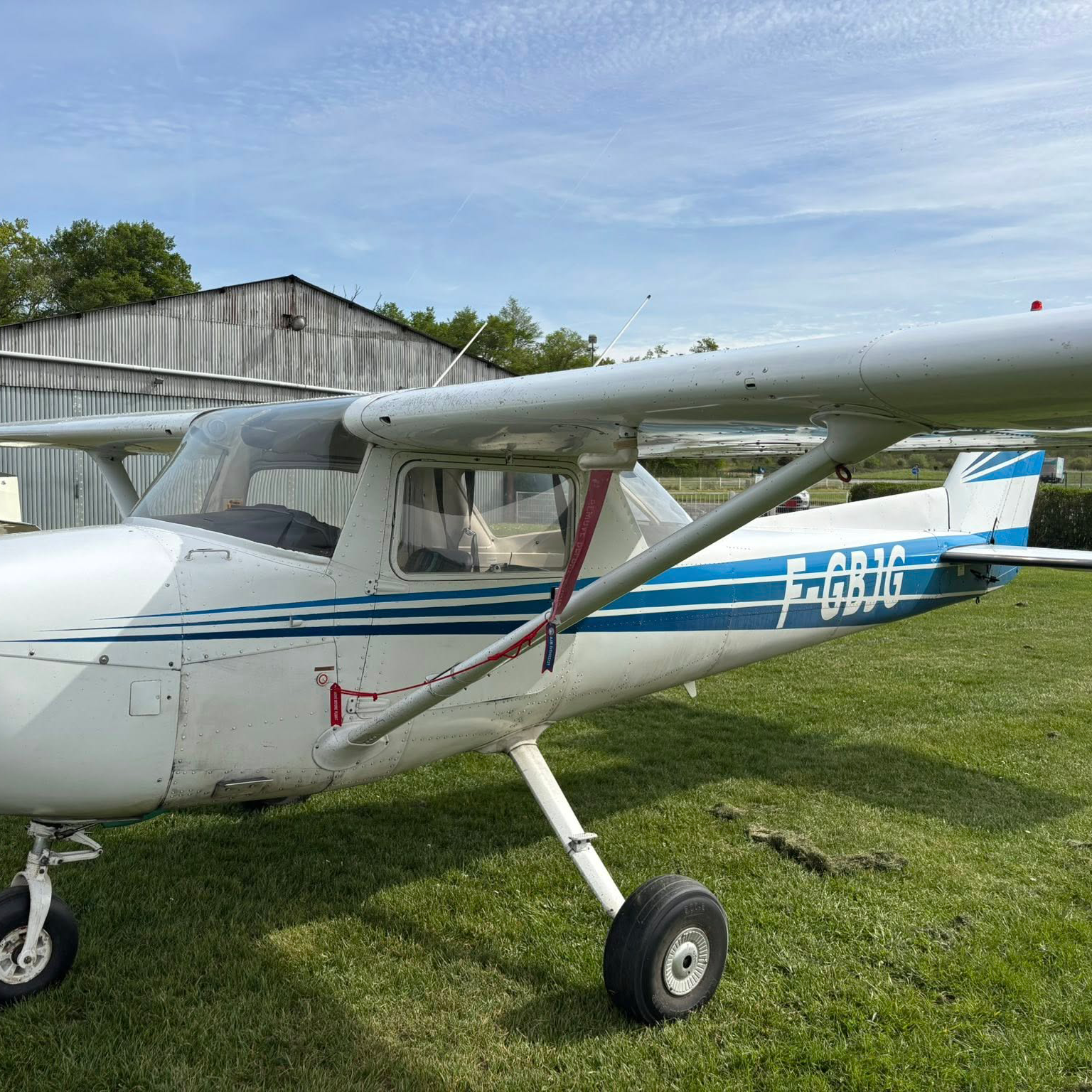 Small white airplane with blue stripes on a grassy field with Quality N Numbers