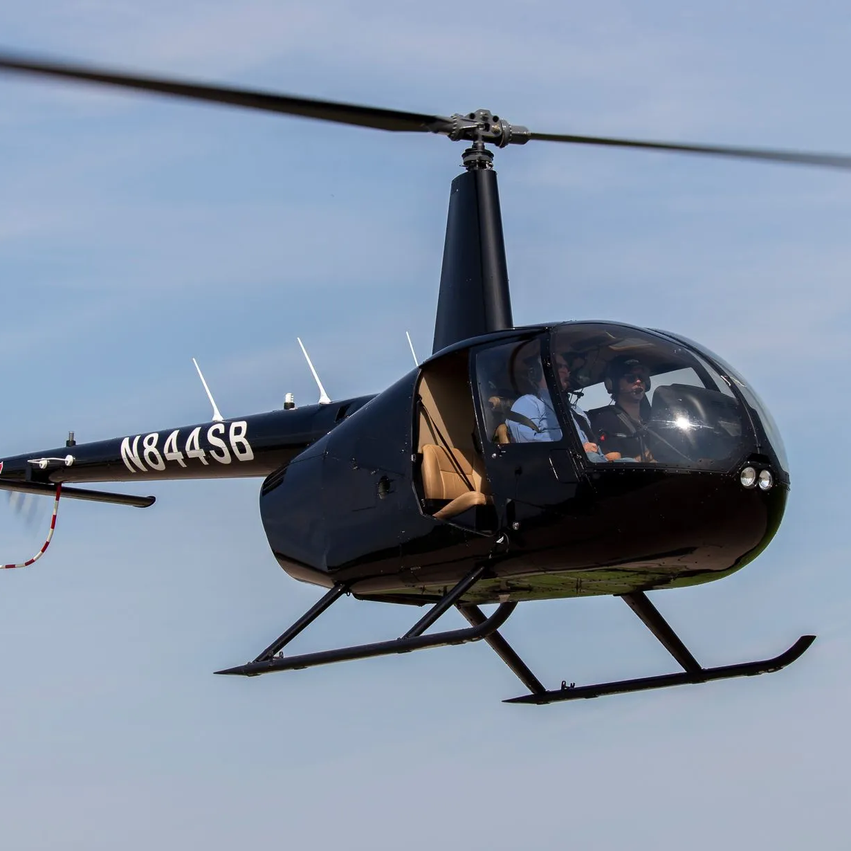 Helicopter flying against a clear blue sky with tail numbers visible. 