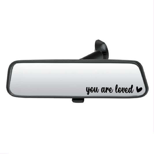 Car mirror with 'you are loved' text on a white background